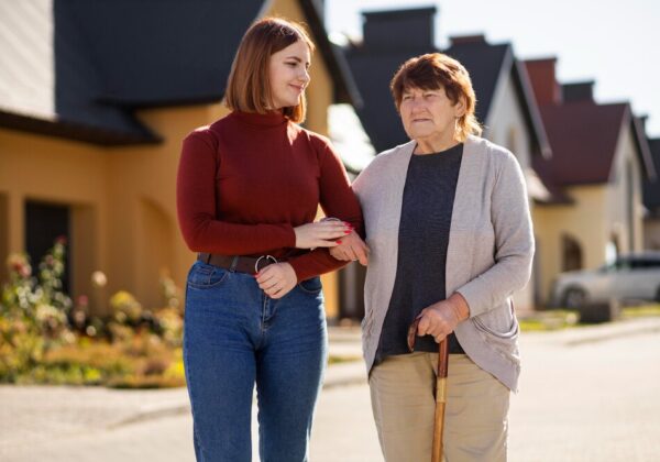 Daughter helping senior mother walk through the home with a gentle smile