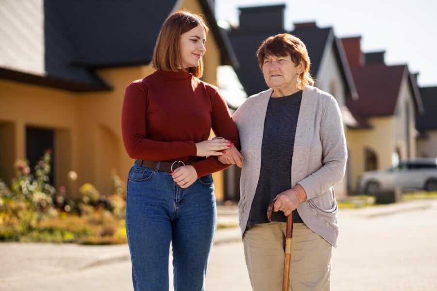 Daughter helping senior mother walk through the home with a gentle smile